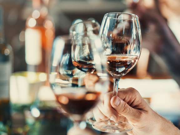 Close-up of guests clinking wine glasses at a tasting.