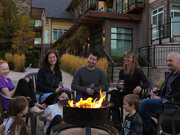 A group enjoying an evening firepit together with kids and adults seated in a circle near the resort.