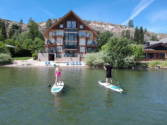 Two guests paddleboarding on the lake in front of Summerland Waterfront Resort & Spa.