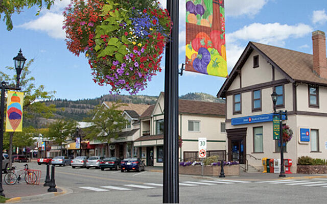 Main street in downtown Summerland with shops, banners, and mountain backdrop