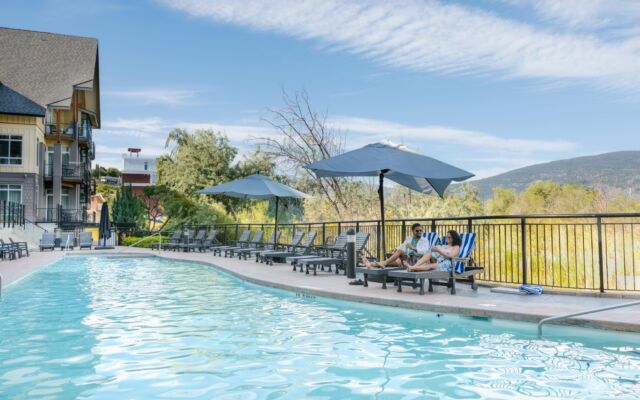 A vibrant resort poolside setting at Summerland Waterfront Resort and Spa showing several lounge chairs arranged around a heated outdoor pool. The sunlit scene suggests relaxation and leisure, with an inviting atmosphere indicative of resort-style comfort.