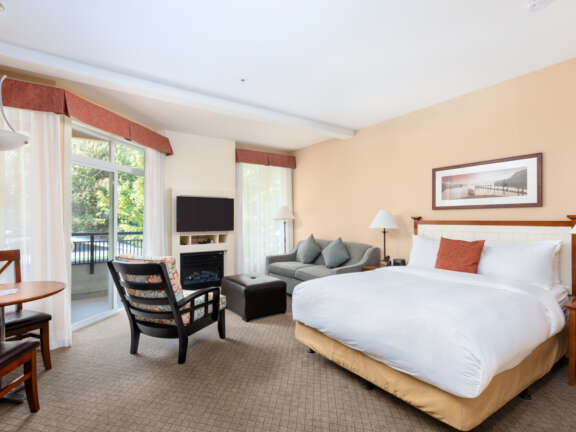 Studio suite with king bed, sofa, fireplace, and balcony at Summerland Waterfront Resort.