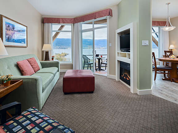Two Bedroom Suite living area with sofa, ottoman, fireplace, and lakeview balcony at Summerland Waterfront Resort & Spa.