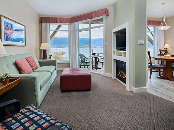 Two Bedroom Suite living area with sofa, ottoman, fireplace, and lakeview balcony at Summerland Waterfront Resort & Spa.